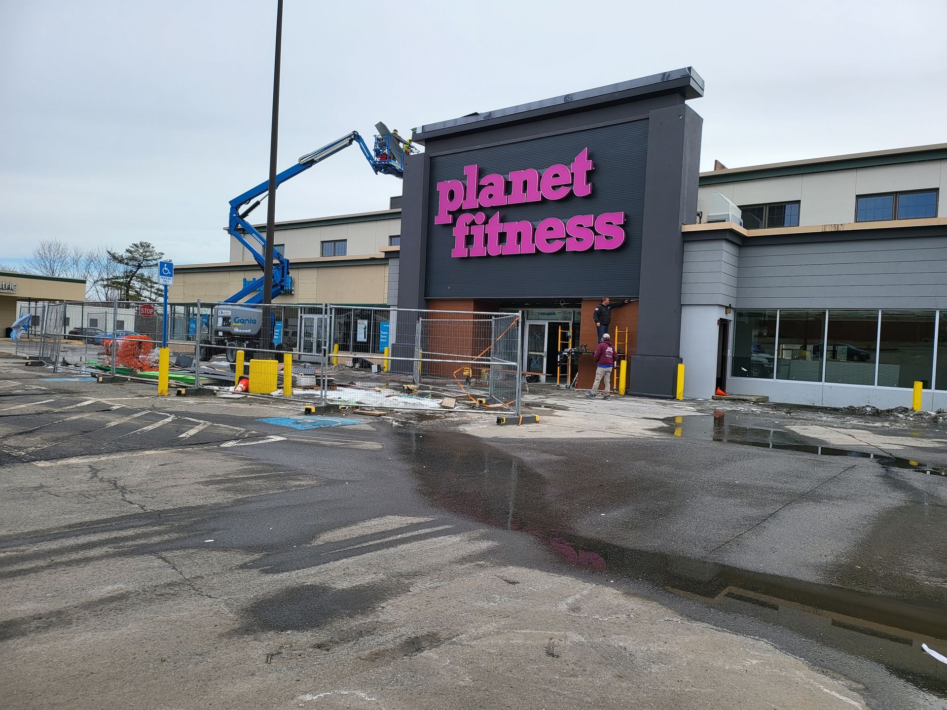 Planet Fitness under construction, with a person, lift equipment, and barrier fencing.