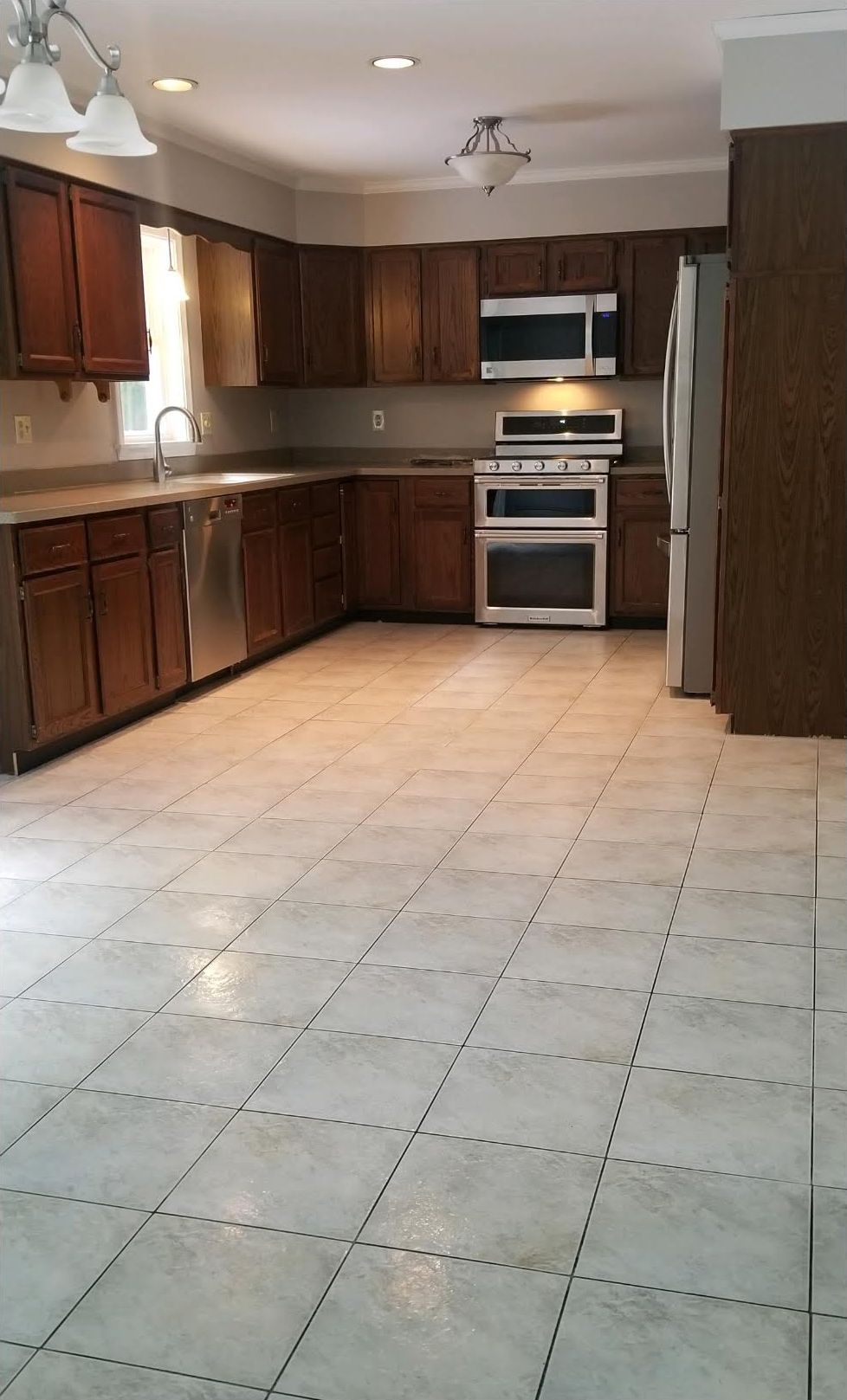 Kitchen with dark wood cabinets, stainless steel appliances, and tiled floor.