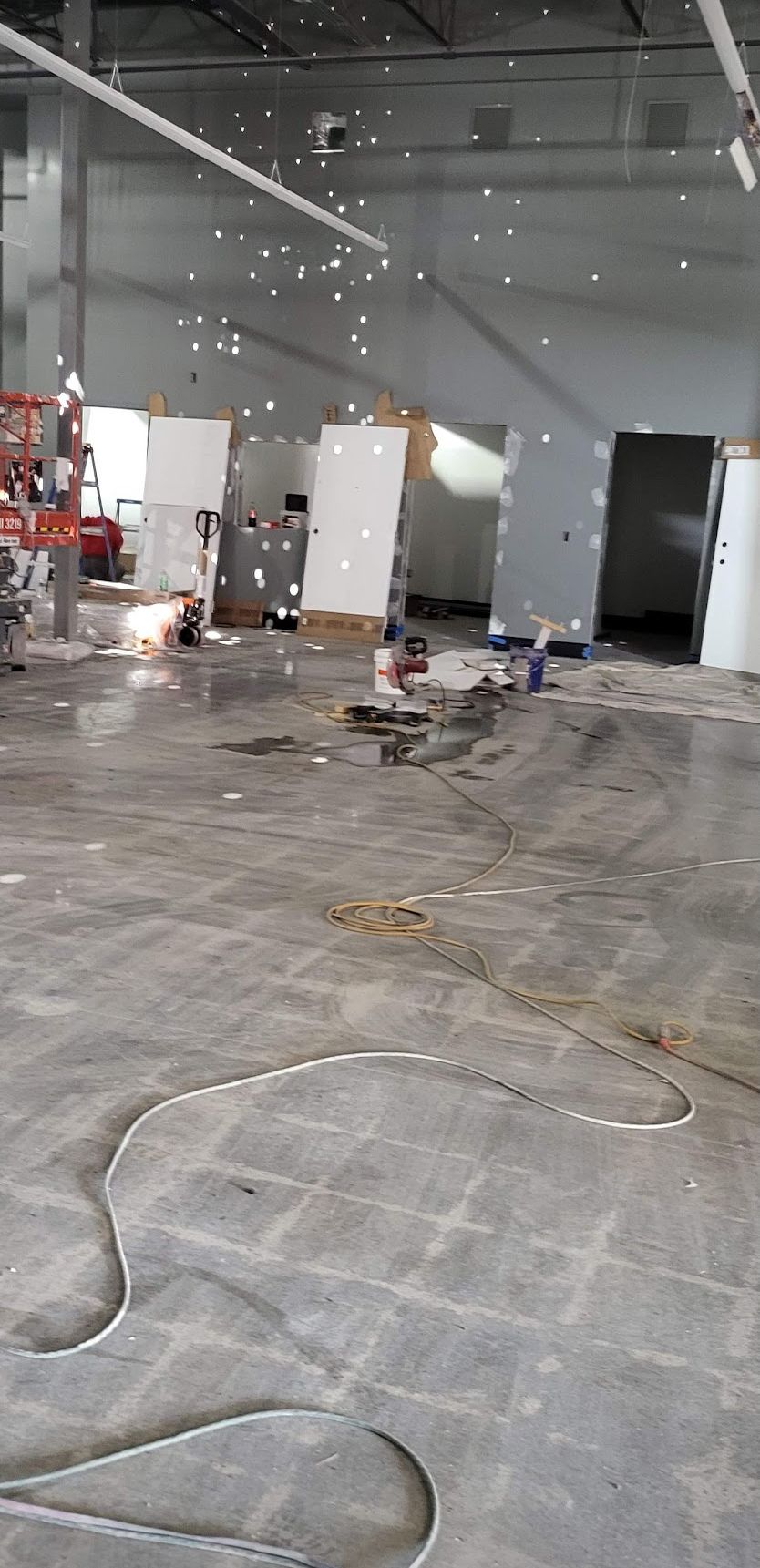 An interior construction site with concrete floor, white walls and tools.