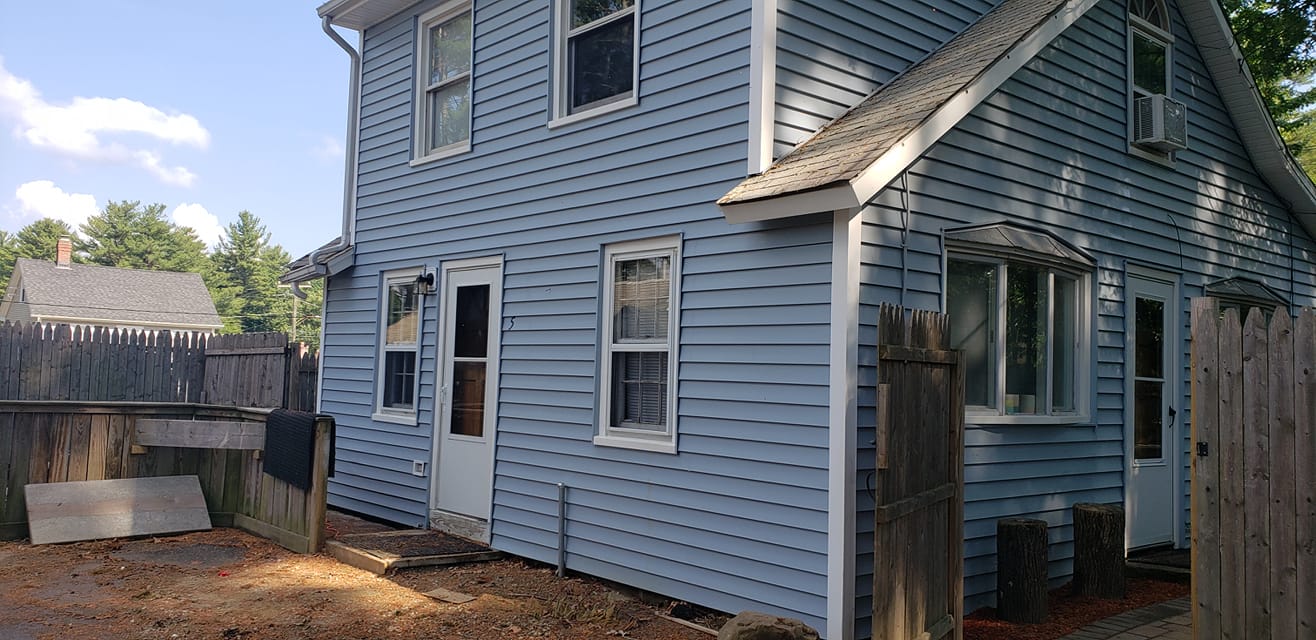 A blue house with a wooden fence in front of it.