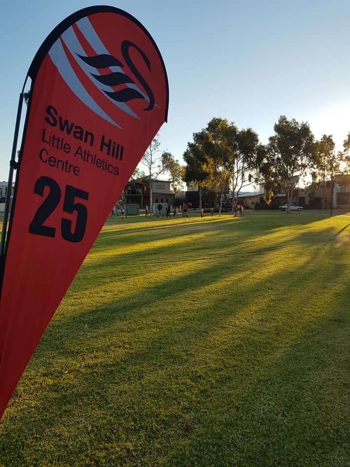 Red flag for Swan Hill Little Athletics Centre, 25. Setting is a grassy field, with people and trees in background.