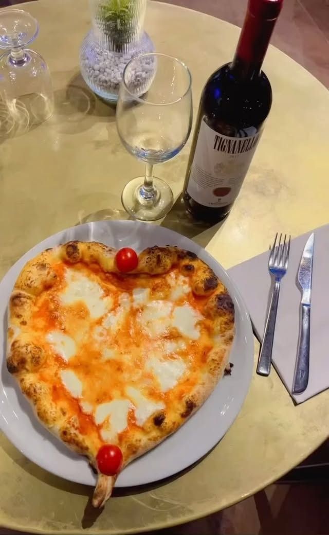 Mani che setacciano una polvere fine, possibilmente farina o zucchero, in una ciotola di vetro.