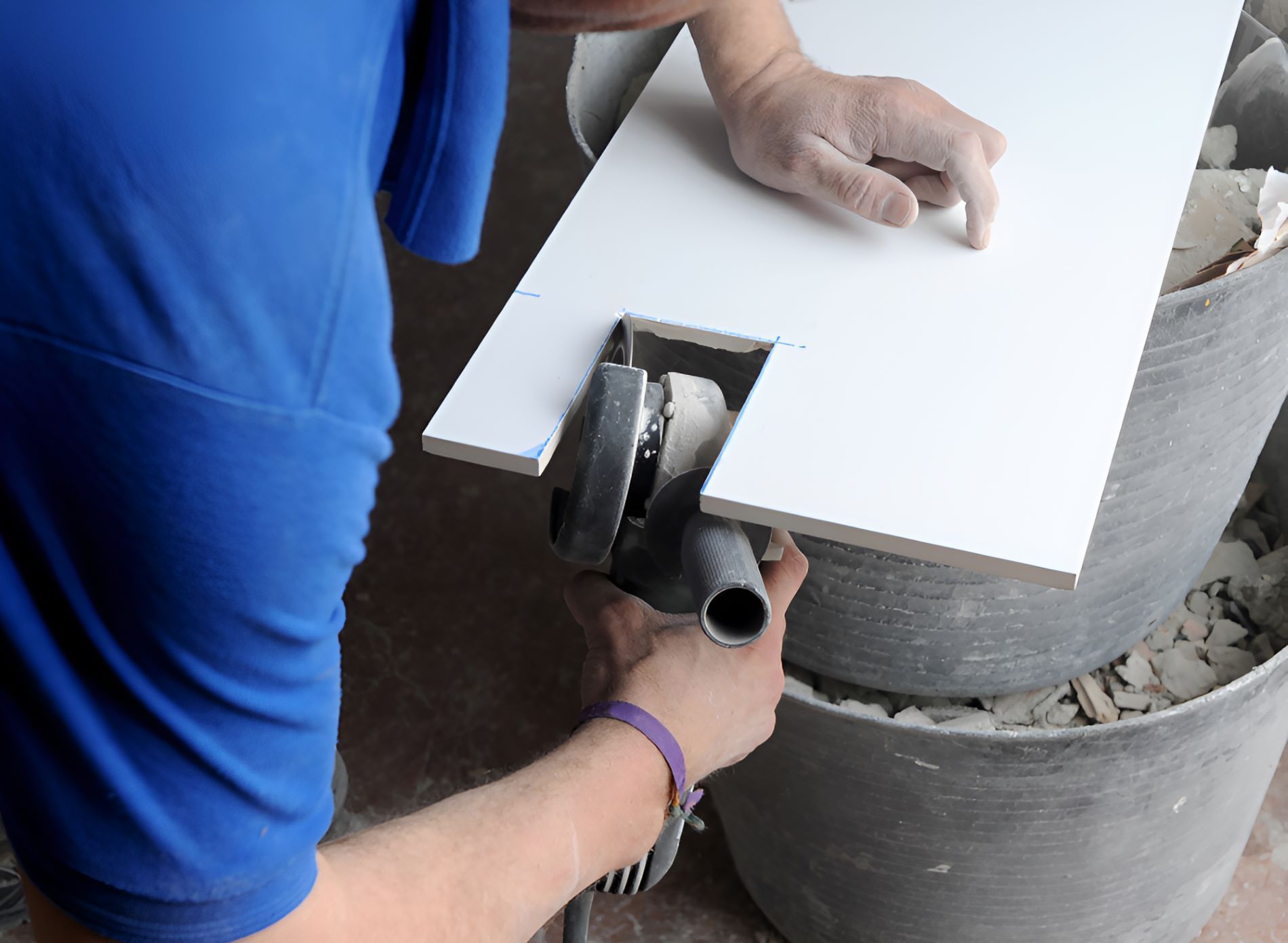 A Man in a Blue Shirt is Cutting a Tile With a Grinder — Accurate Tiling MNC In Dunbogan, NSW