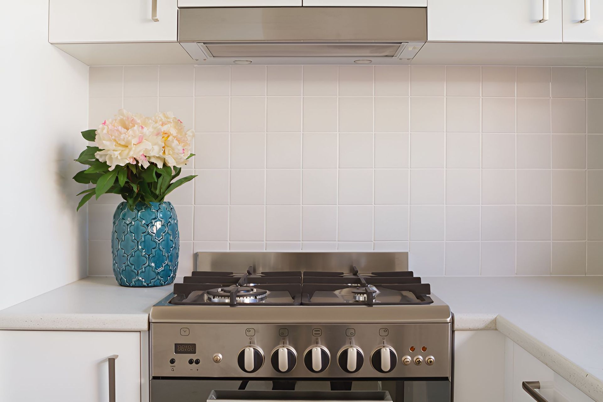 A Stove With a Vase of Flowers on Top of It in a Kitchen — Accurate Tiling MNC In Dunbogan, NSW
