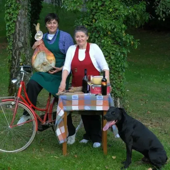 Due donne sedute a un tavolo con un cane e una bicicletta