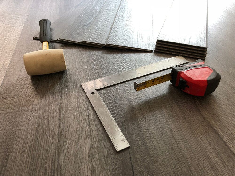 A Hammer, Ruler, and Tape Measure Are on a Wooden Floor — John Chisholm Flooring in Dimbulah, QLD