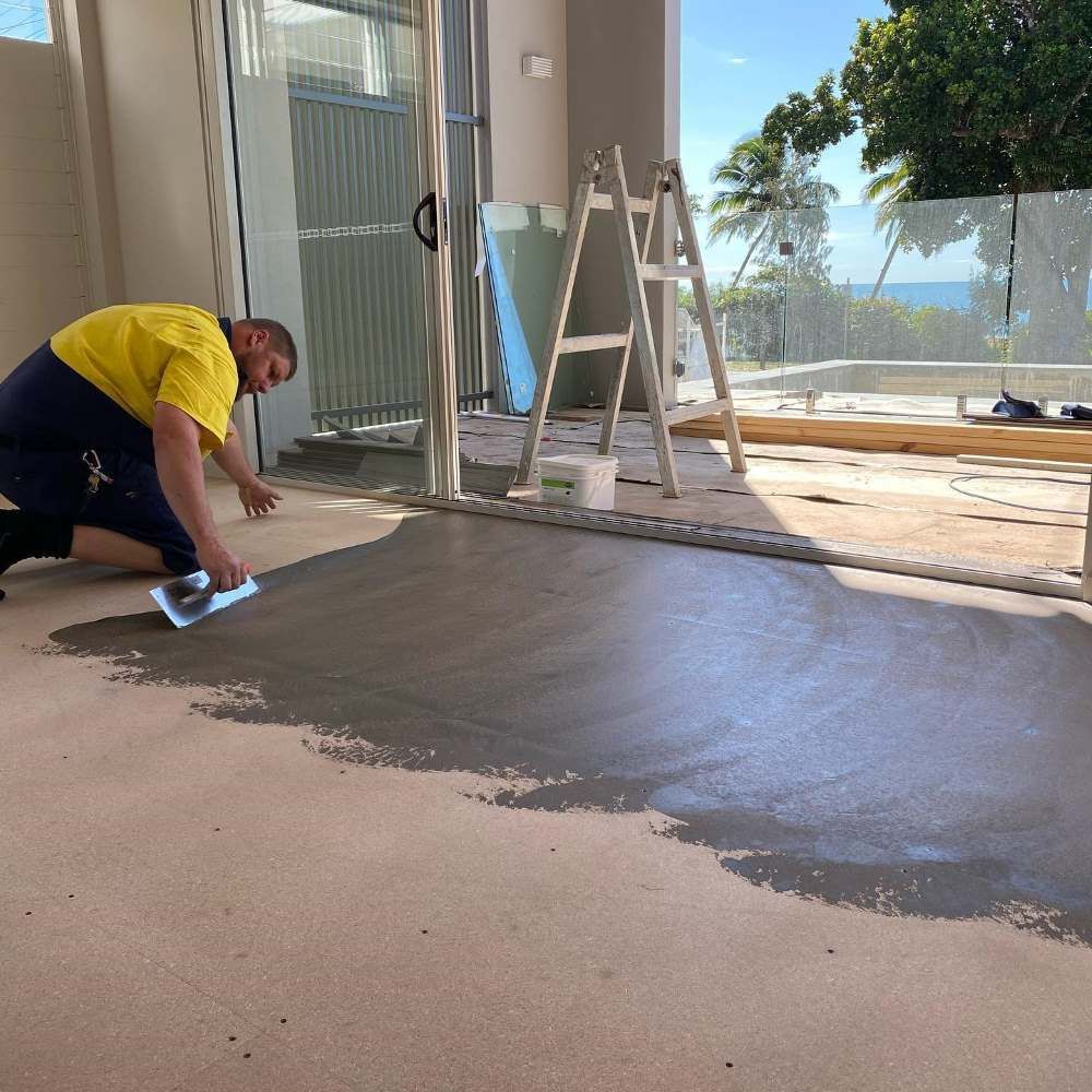 Man is Kneeling on the Floor Using a Trowel — John Chisholm Flooring in Manunda, QLD