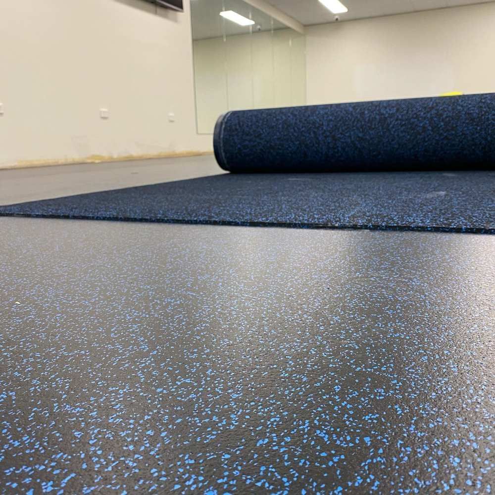 A Roll of Blue Rubber Flooring is Sitting on Top of a Black Floor — John Chisholm Flooring in Manunda, QLD