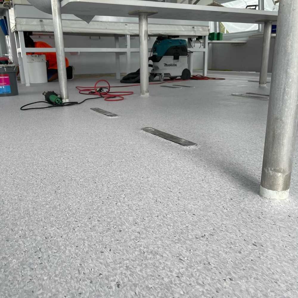 A White Carpeted Floor With a Metal Pole in the Foreground — John Chisholm Flooring in Manunda, QLD