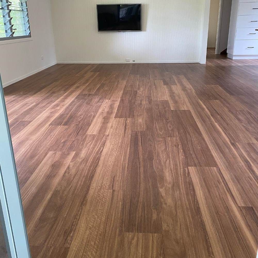A Living Room With a Wooden Floor and a Flat Screen Tv on the Wall — John Chisholm Flooring in Manunda, QLD
