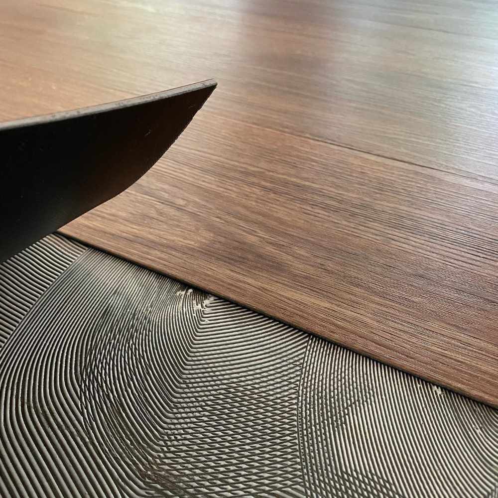 A Man is Installing Vinyl Flooring — John Chisholm Flooring in Mareeba, QLD