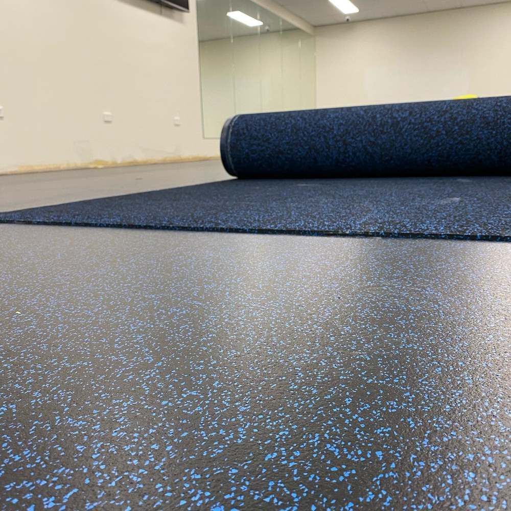 A Roll of Blue Rubber Flooring is Sitting on Top of a Black Floor — John Chisholm Flooring in Mareeba, QLD