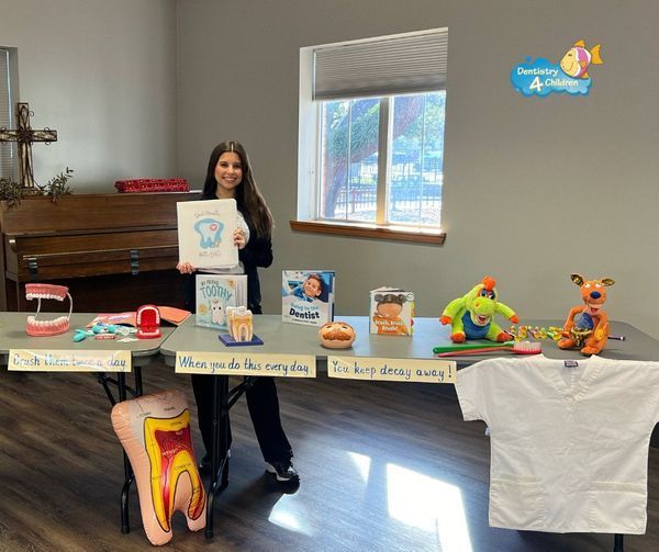 A woman is standing in front of a table with a tooth model on it.