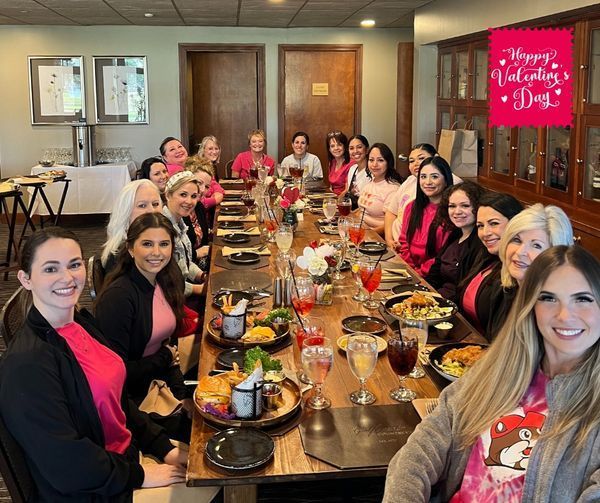 A group of women are sitting at a long table with plates of food.