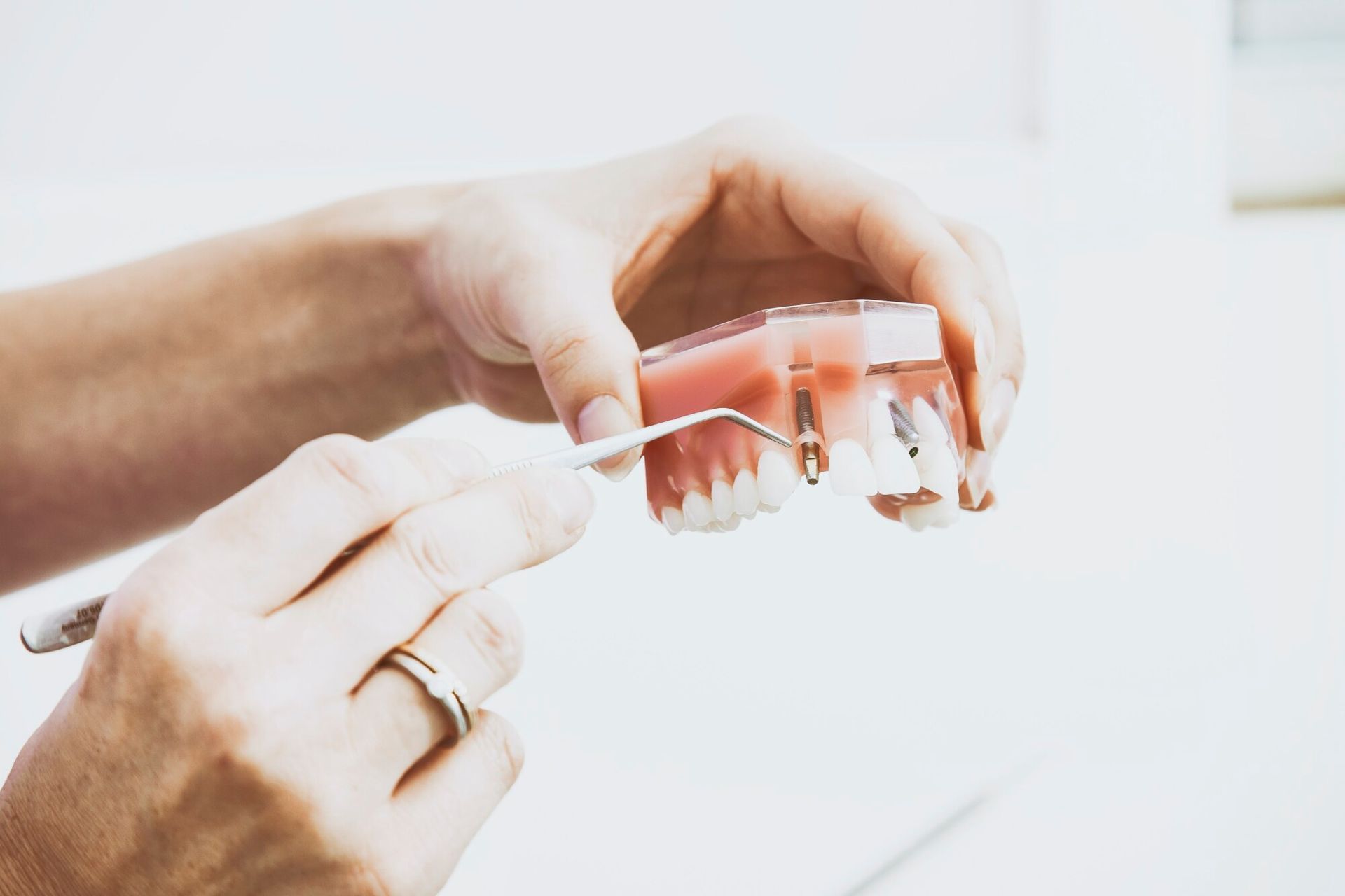 a person is holding a model of teeth with a dental tool