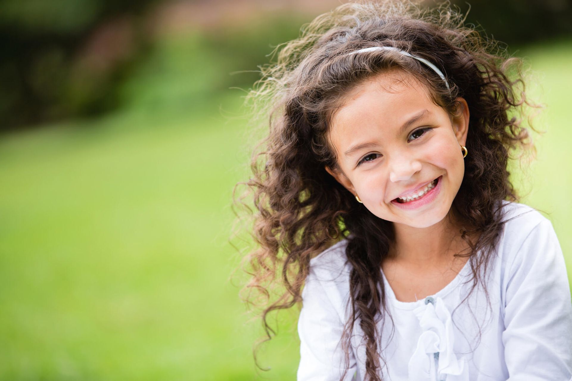 A little girl with curly hair is smiling for the camera.