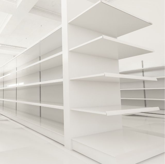 Estantes blancos vacíos en una tienda, vista en ángulo.