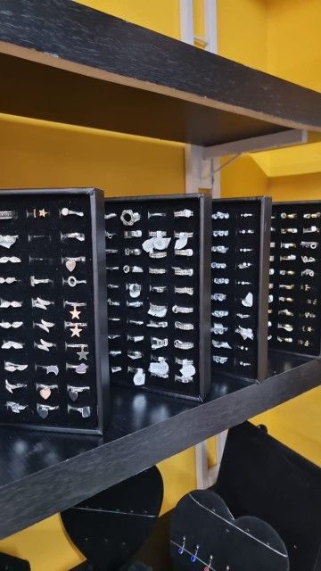 Anillos expuestos en bandejas de terciopelo negro en los estantes de una joyería. Fondo amarillo y negro.