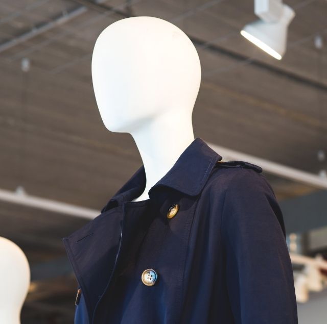 Maniquí con gabardina azul marino; entorno minorista.