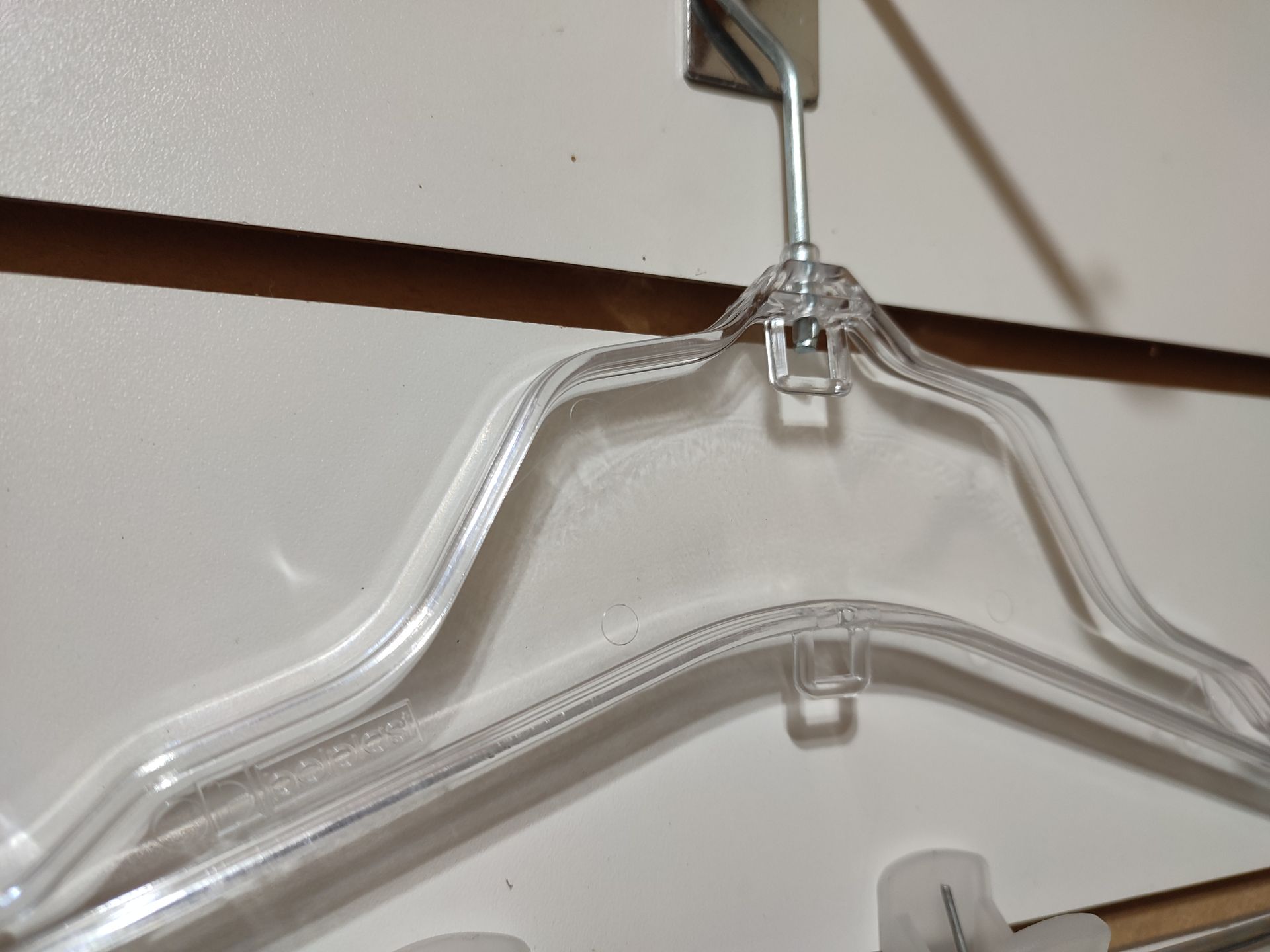 Percha de ropa de plástico transparente colgada en una pared blanca.