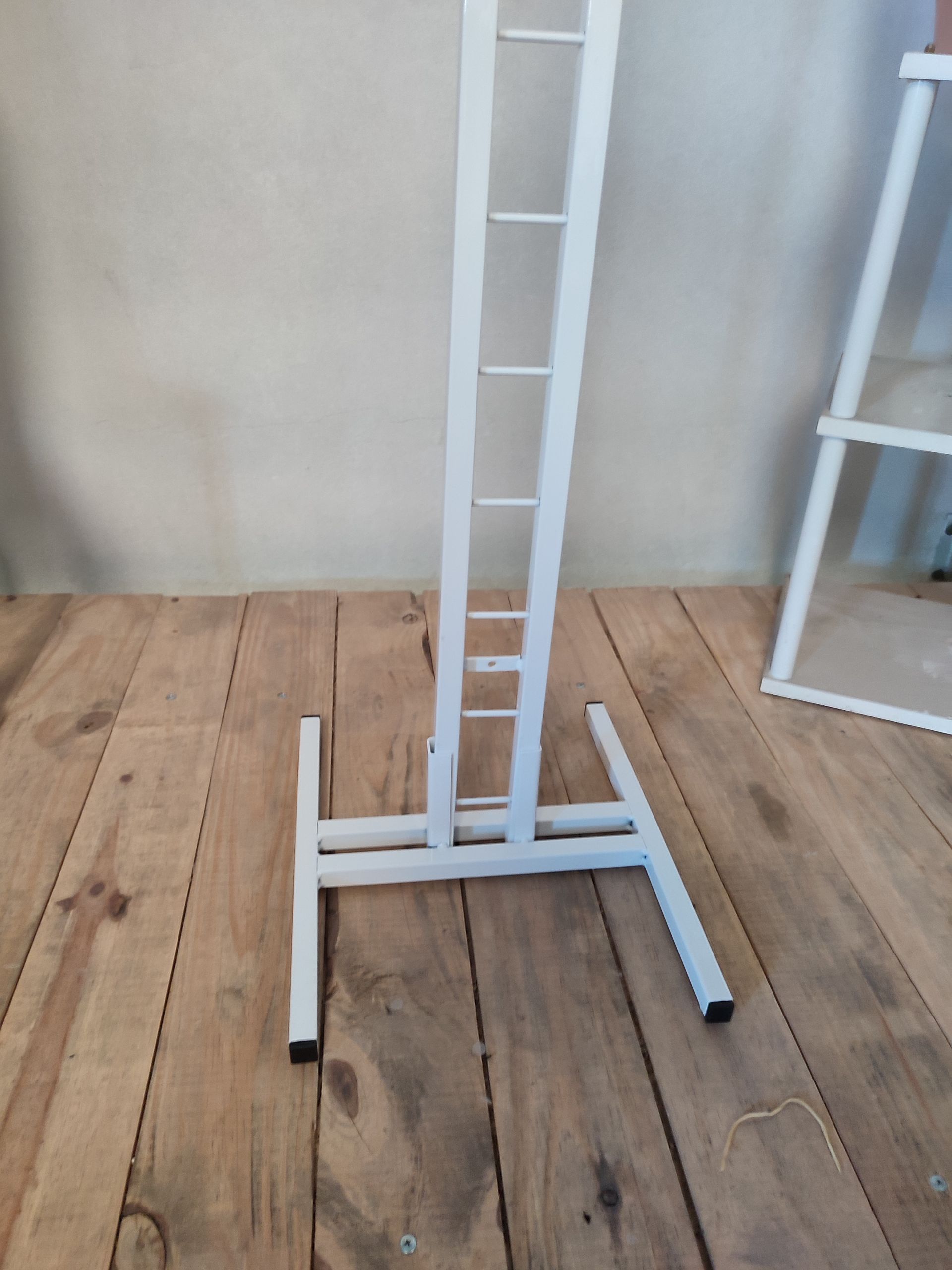 Perchero de metal blanco sobre suelo de madera.