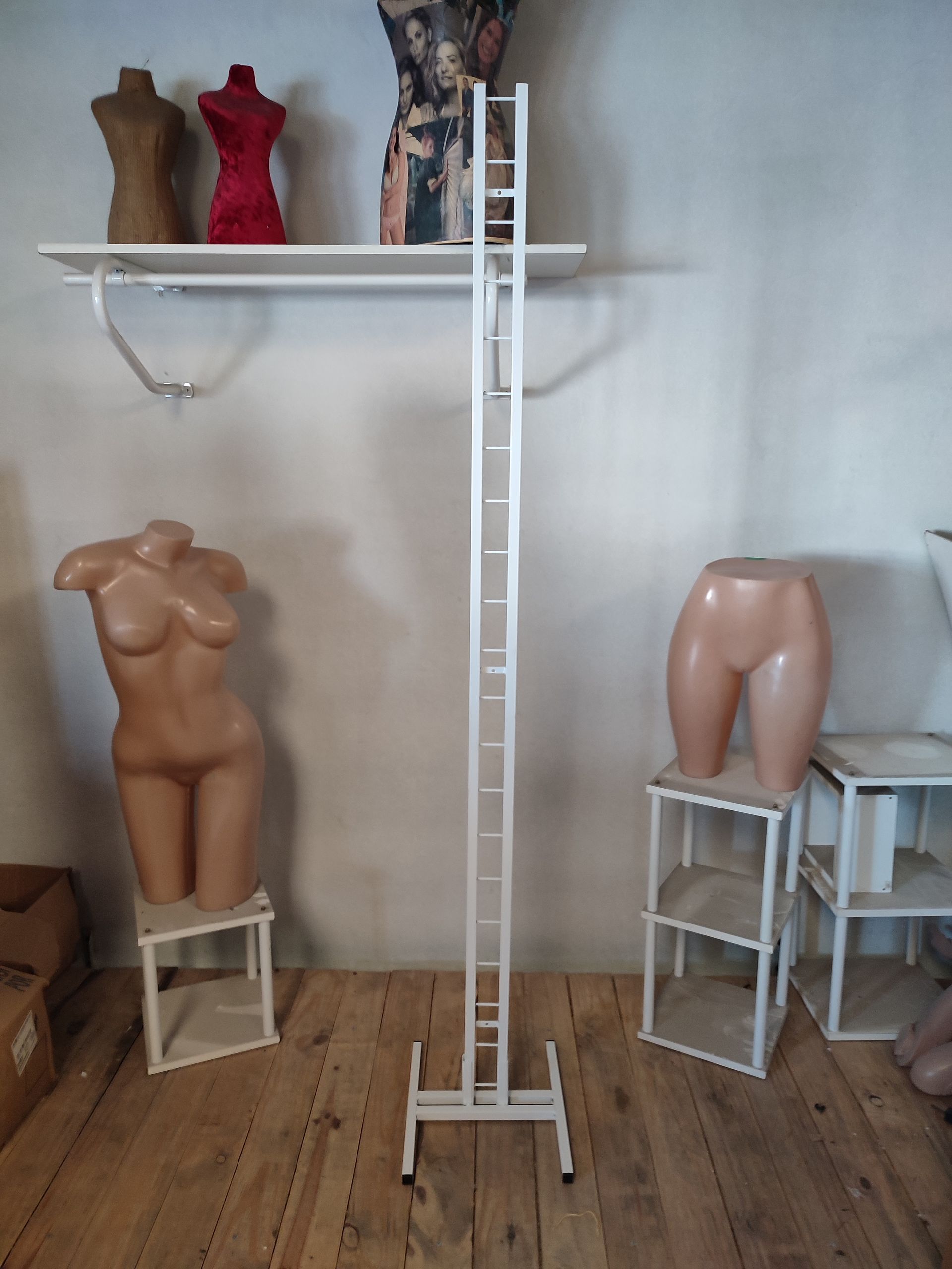 Interior de tienda de ropa con maniquíes, estanterías y un expositor de metal.