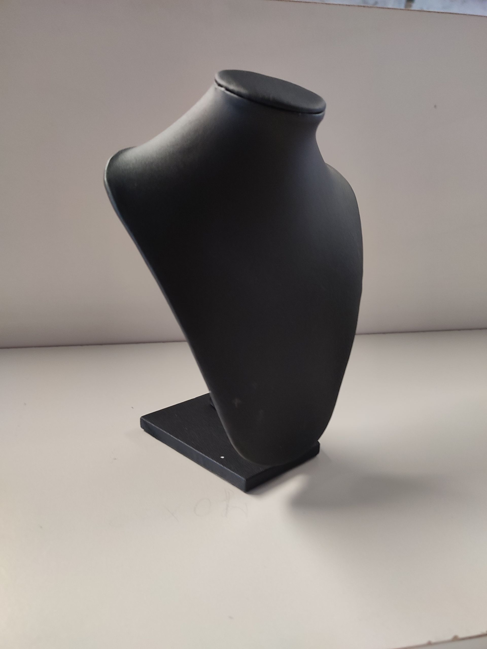 Busto de exhibición de joyería negra sobre una superficie blanca, que muestra un collar.