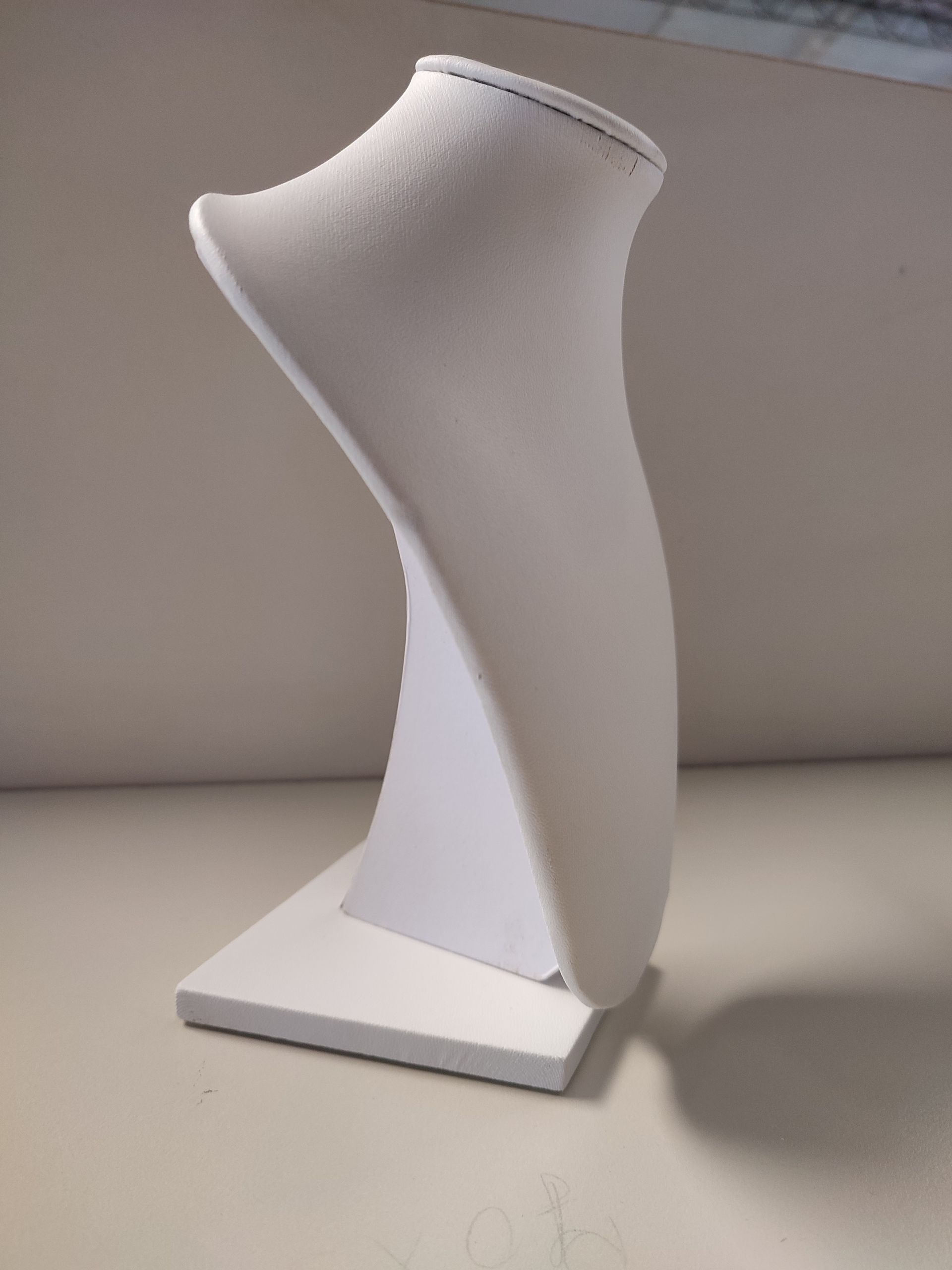 Busto expositor de joyería de color blanco, con base plana y cuello curvo.