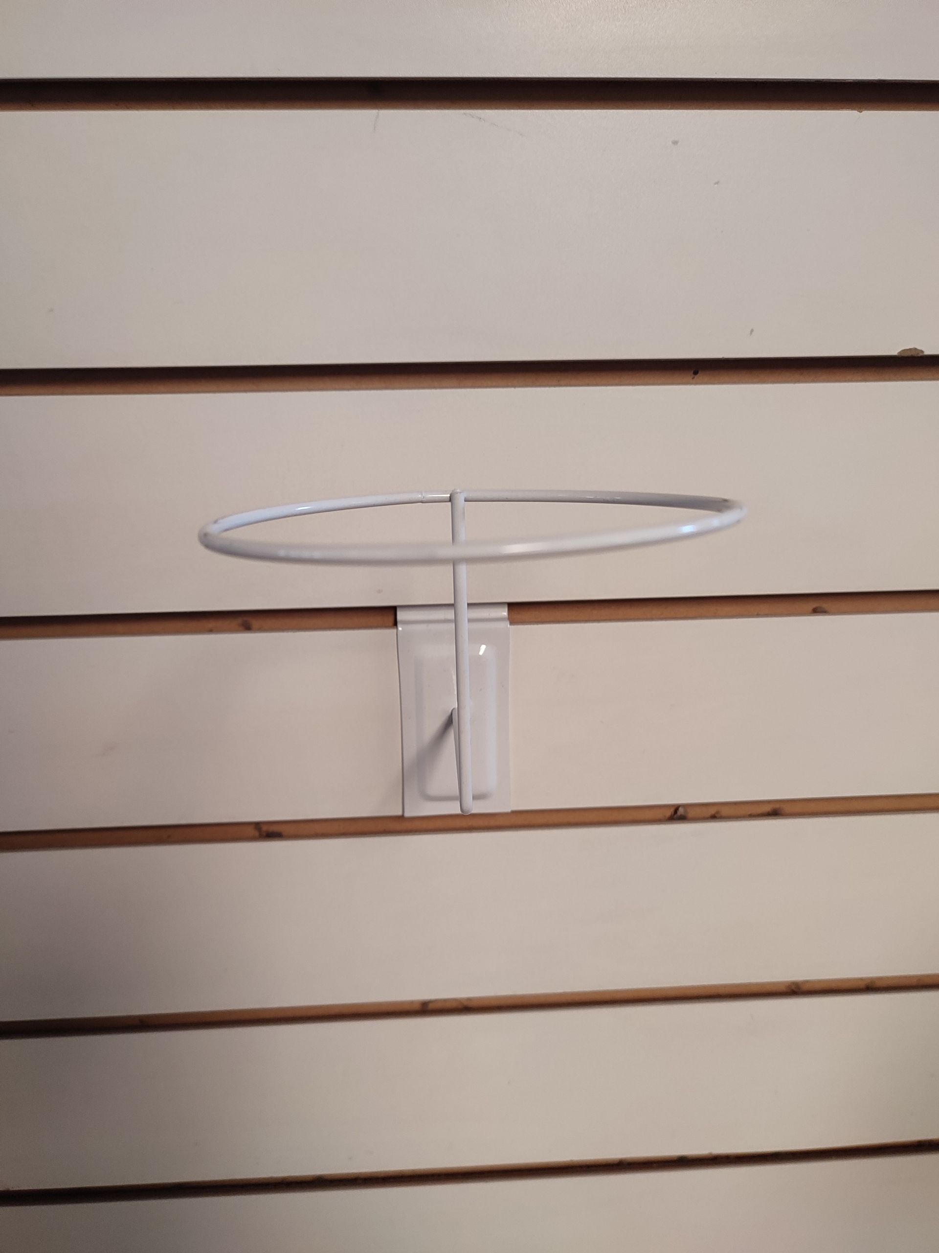 Expositor de sombreros blancos montado sobre pared de listones.