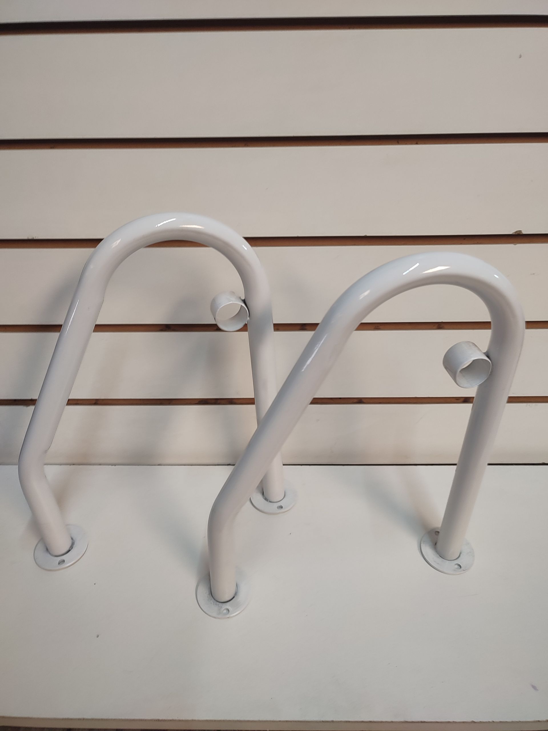 Aparcabicicletas de color blanco con forma de arco.