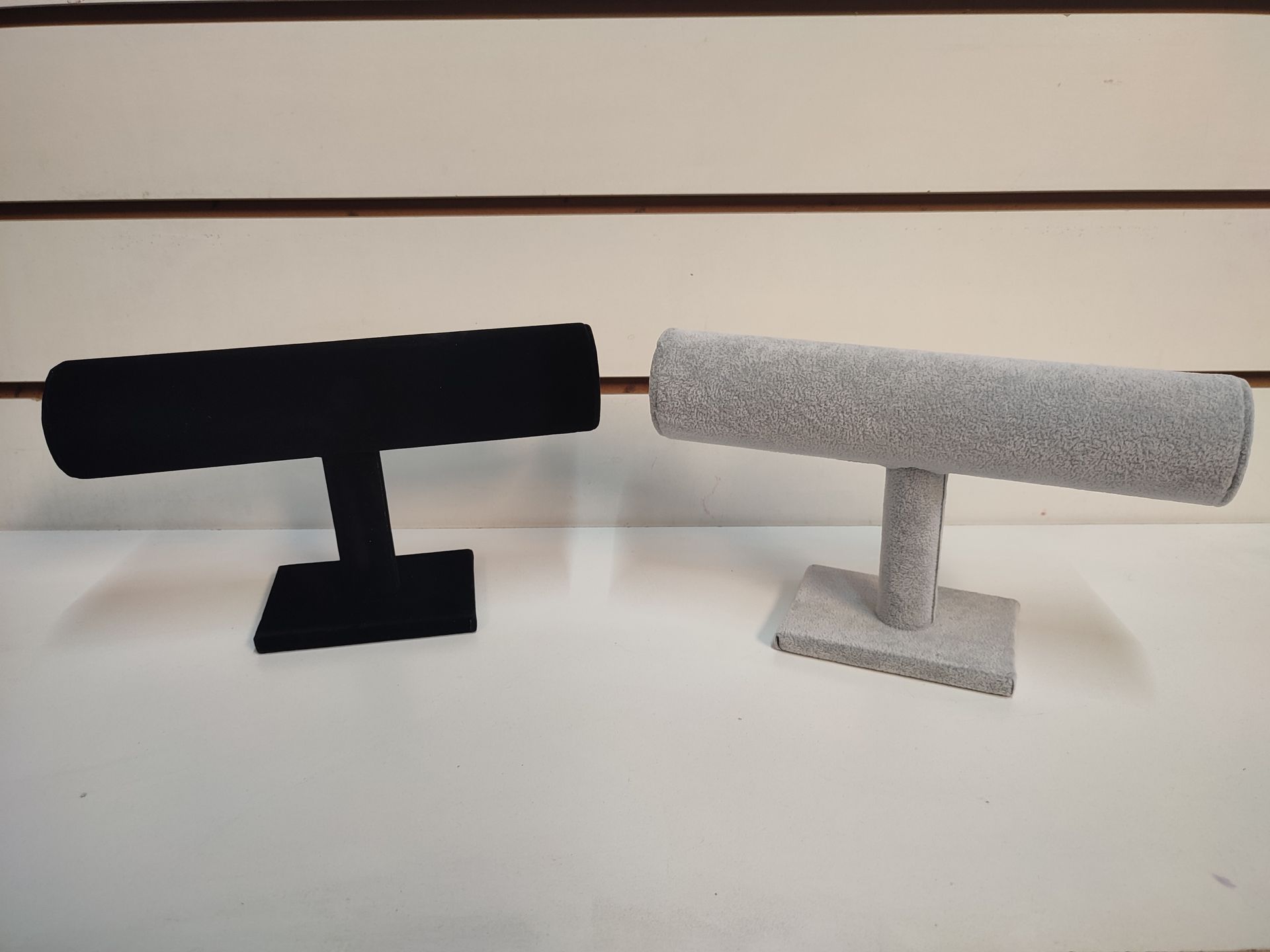 Dos expositores de joyas, uno negro y otro gris, con forma de T.