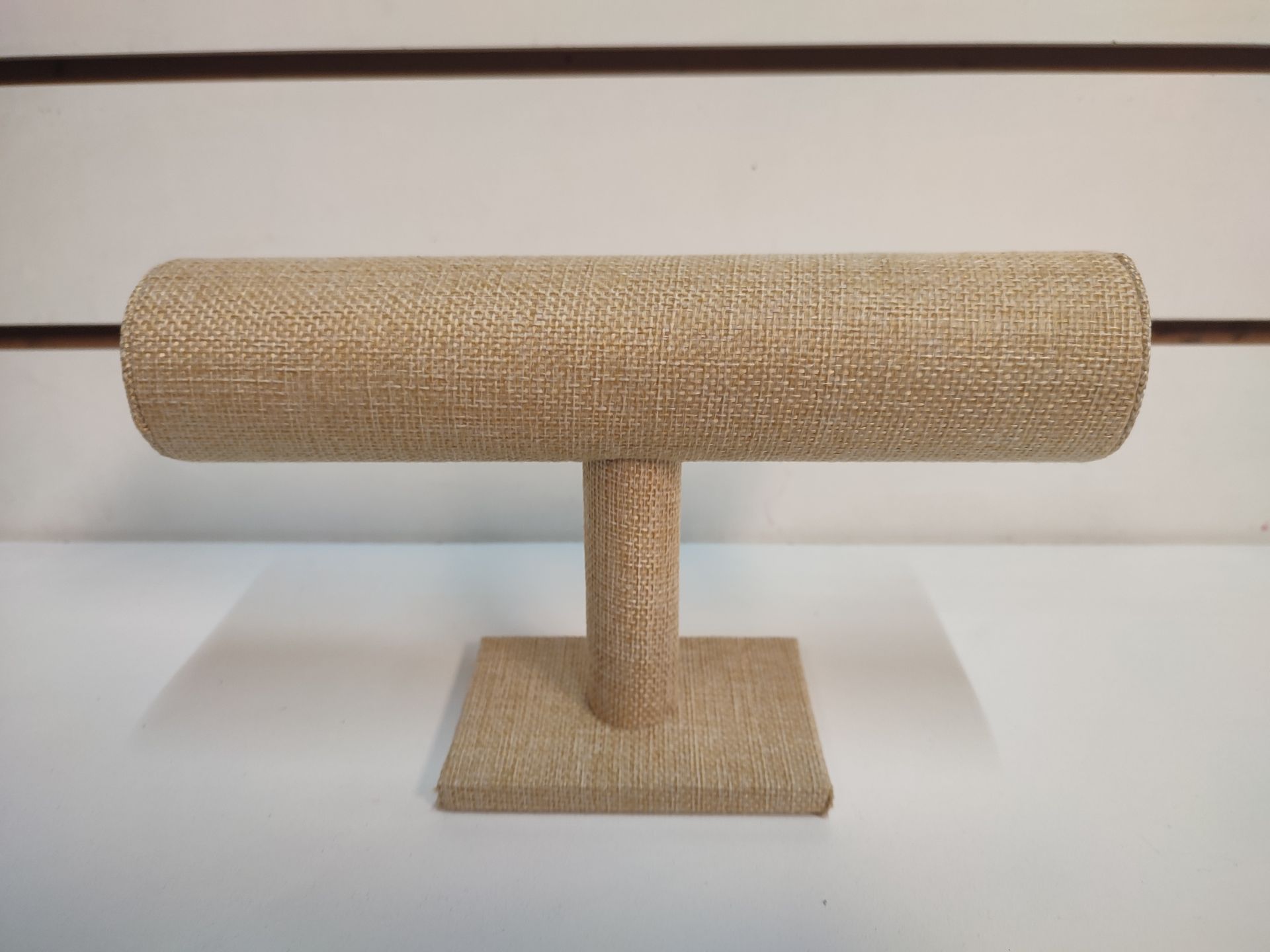 Expositor de joyas revestido en tela color canela, con barra horizontal