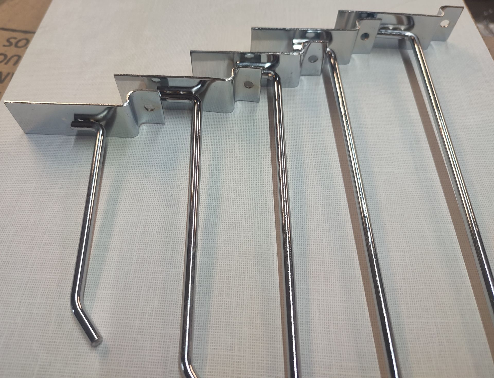 Cinco ganchos cromados para exhibición minorista de diferentes longitudes.