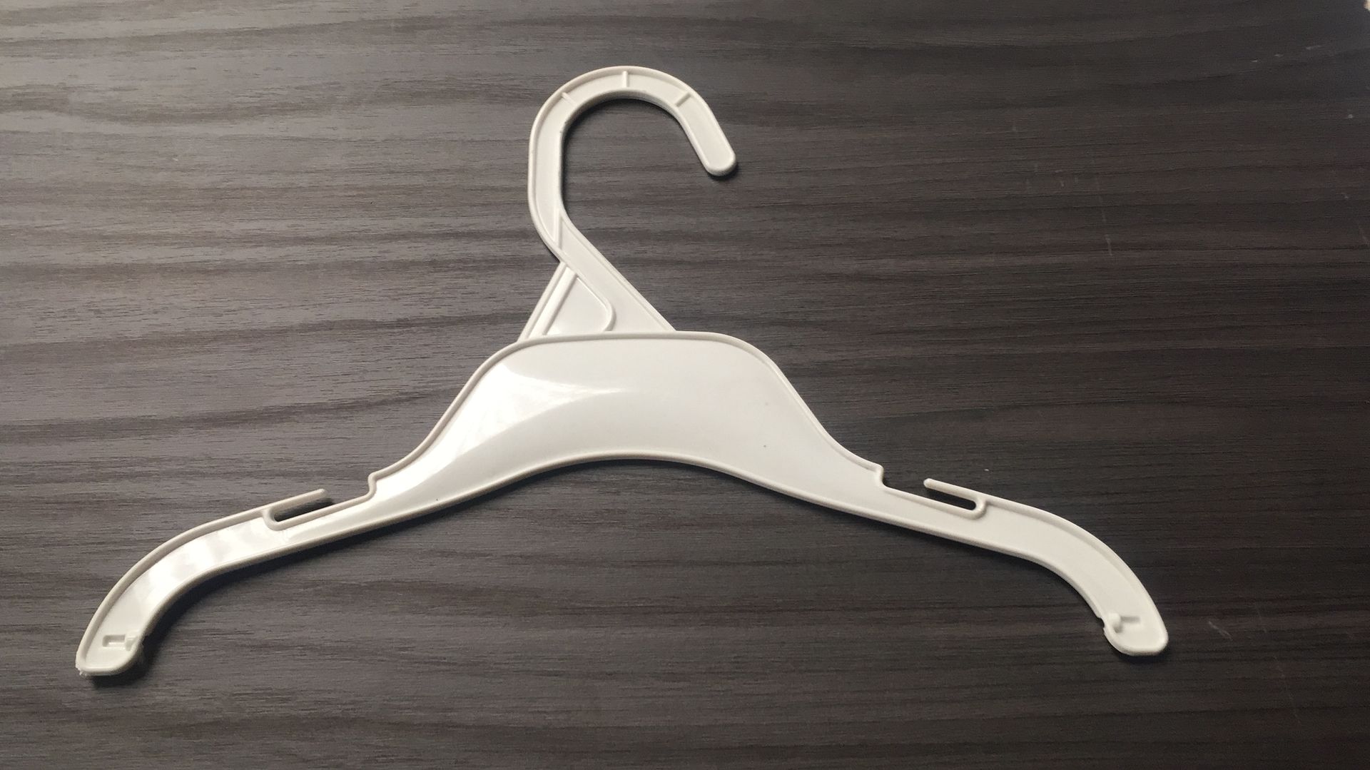 Percha de ropa de plástico blanco sobre una superficie de madera oscura.