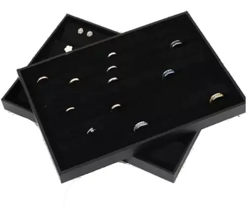 Dos bandejas de exhibición de joyas negras, que contienen varios anillos y aretes, sobre un fondo blanco.
