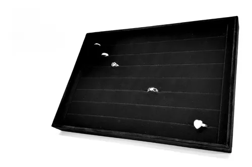 Bandeja expositora de joyas de color negro con anillos en ranuras individuales.