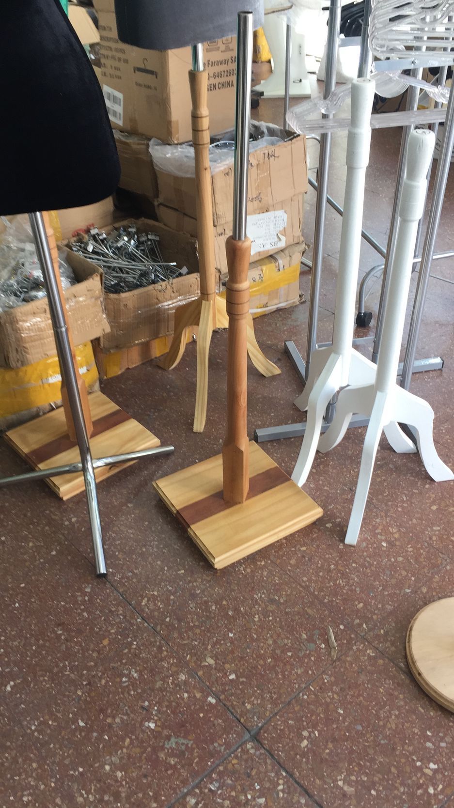 Diversos maniquíes con bases de madera y metal sobre un suelo de baldosas marrones.