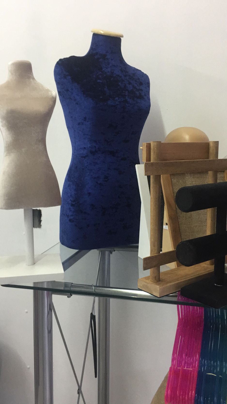 Dos maniquíes, uno de ellos forrado en terciopelo azul, sobre una mesa. Cerca hay varios materiales de artesanía.