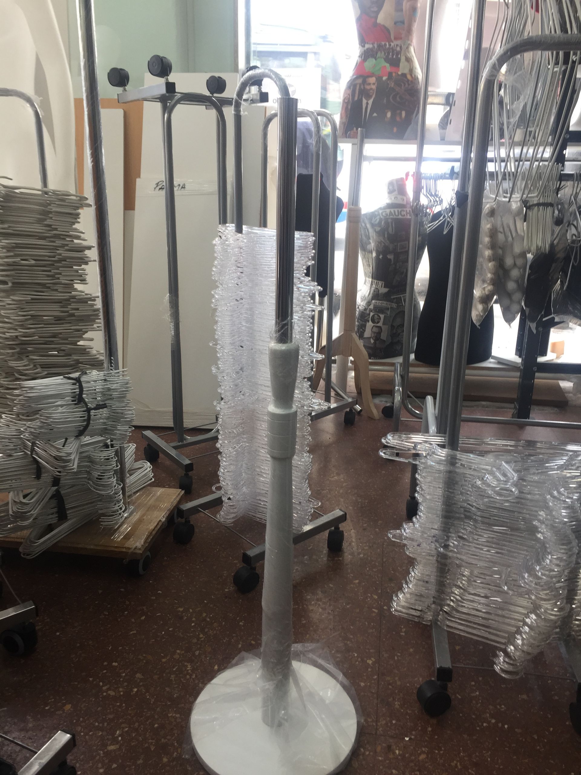 El interior de una tienda de ropa muestra un nuevo maniquí de plástico y otros estantes para prendas.