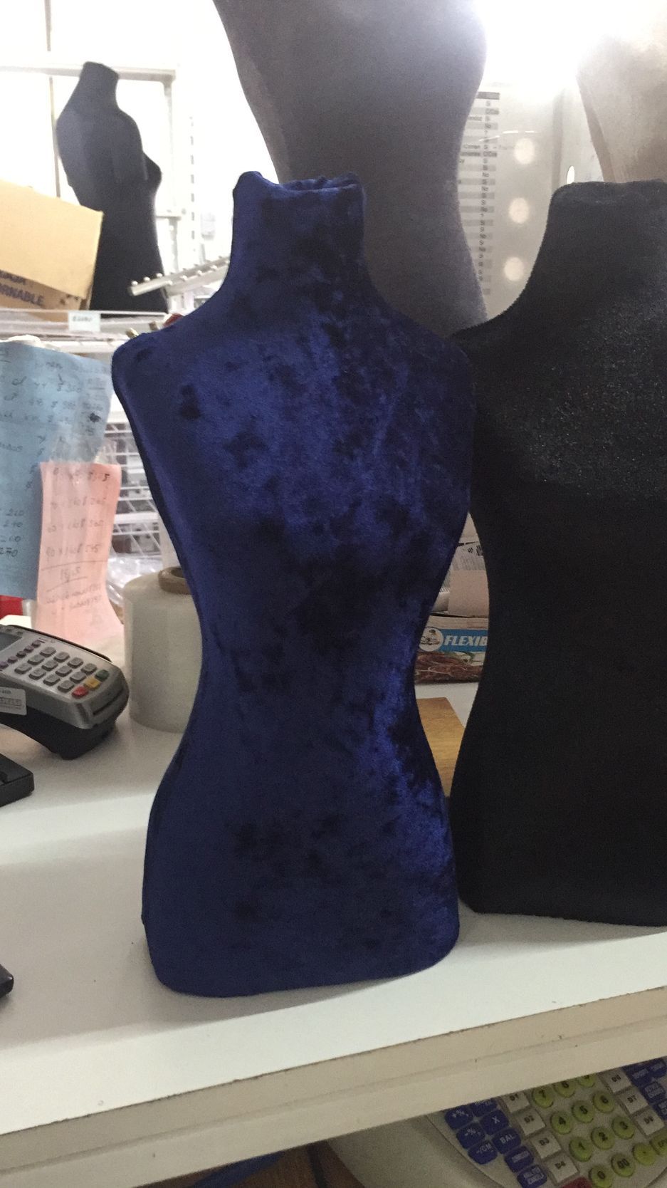 Busto de joyería de terciopelo azul en exhibición junto a otros bustos.