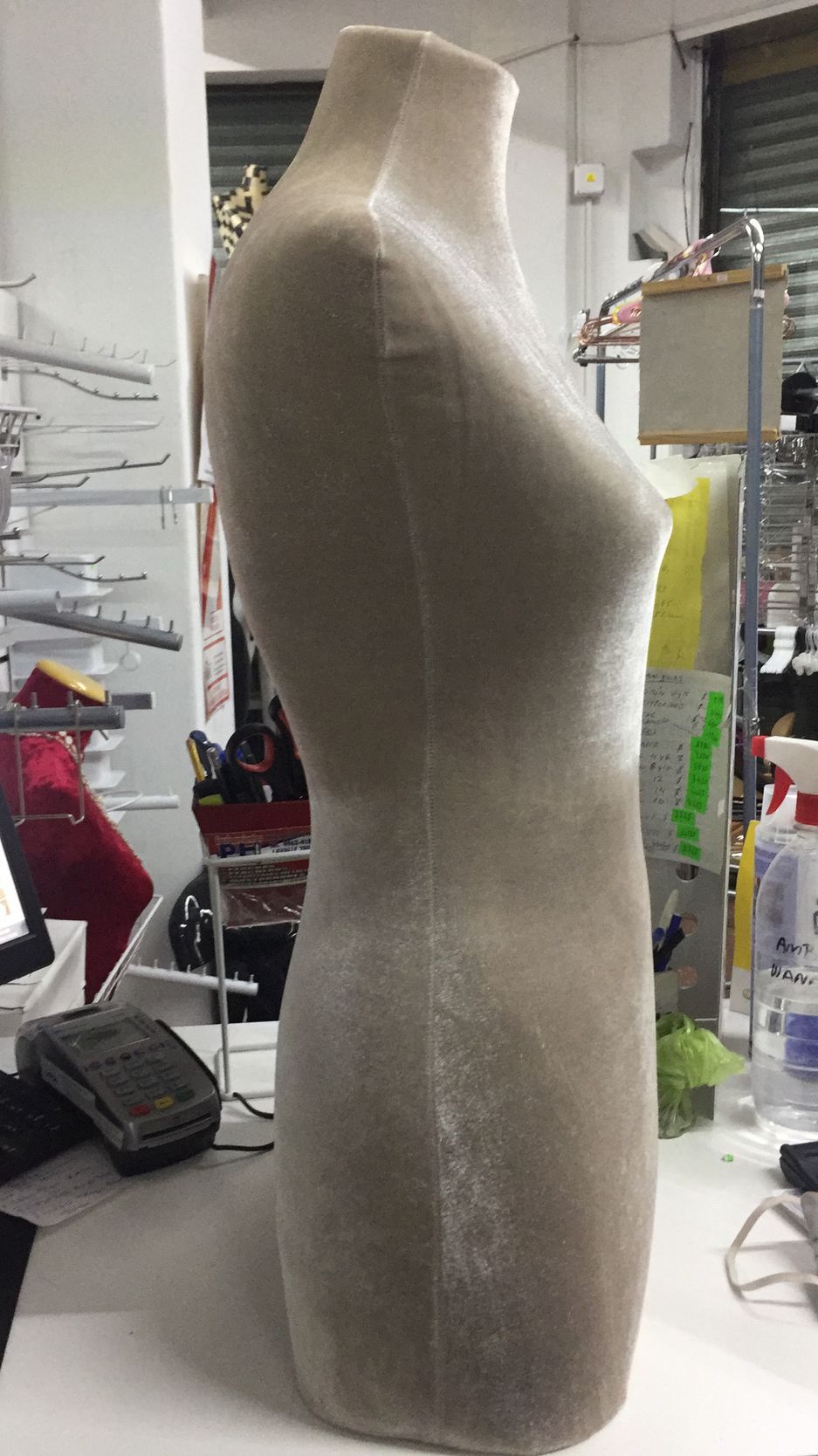 Maniquí de tela beige, con torso y cuello visibles, de pie sobre una mesa blanca en un taller.