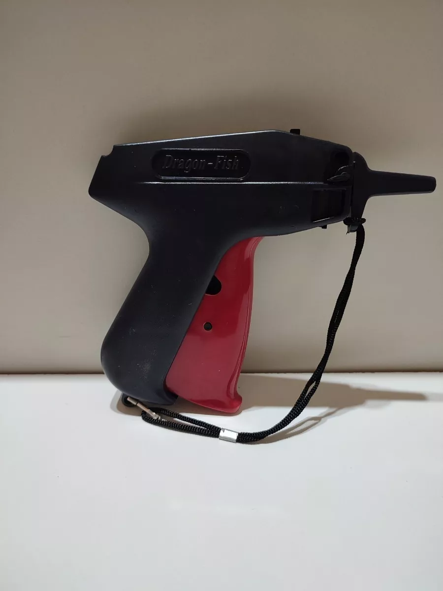 Escáner de código de barras portátil negro y rojo sobre una superficie blanca con una correa de muñeca.