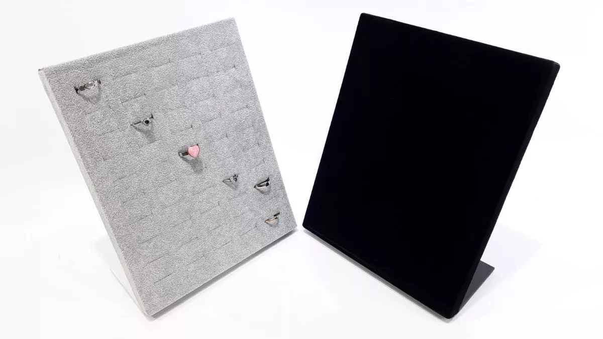 Dos expositores de joyas inclinados, de color gris y negro, con porta anillos.