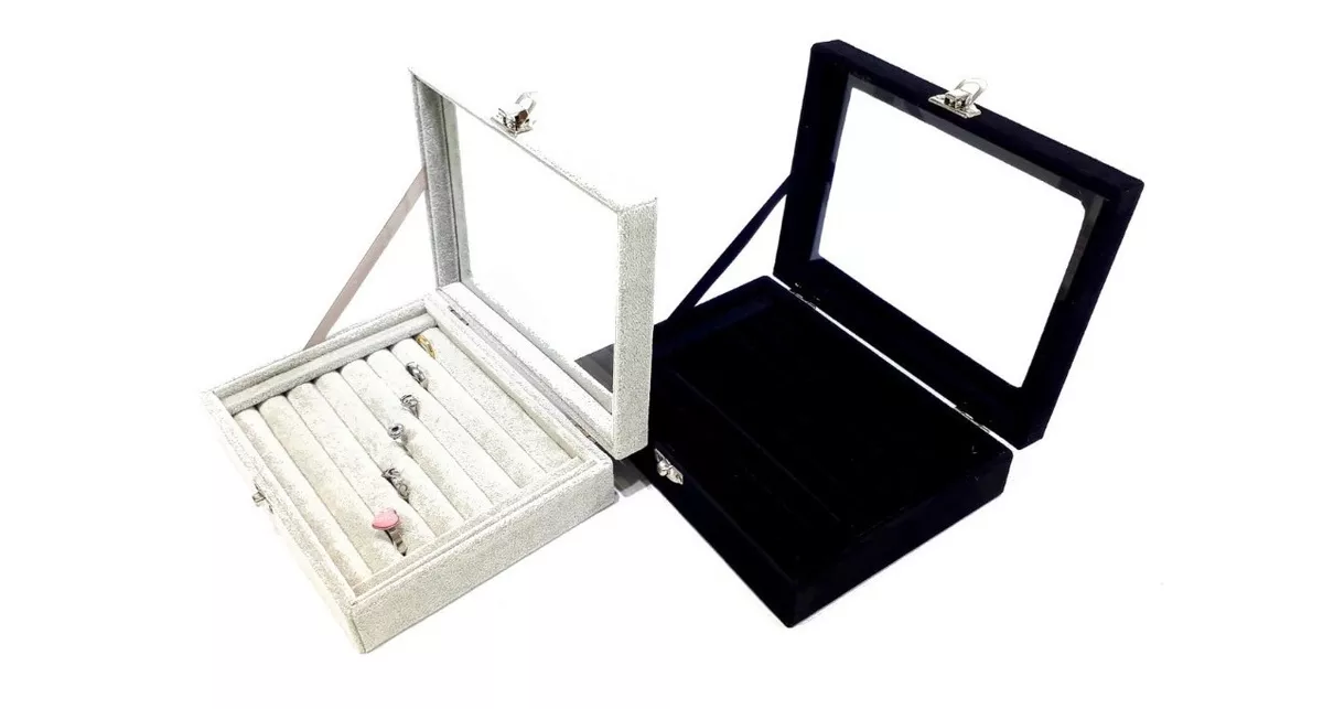 Dos cajas expositoras de joyas abiertas, de color blanco y negro, con tapas de cristal.