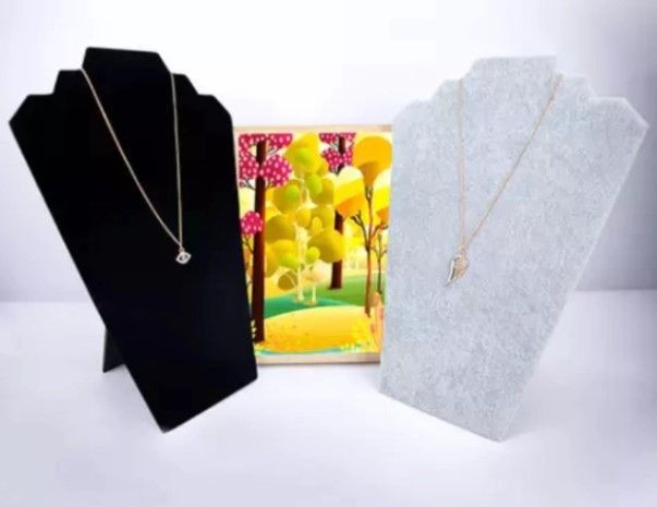 Exhibidores de collares en blanco y negro que sostienen collares de oro; una impresión artística en el centro.