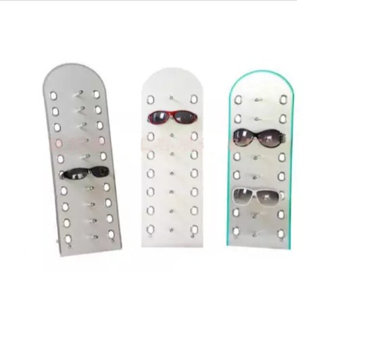 Tres expositores de gafas, de color gris, blanco y verde azulado, que contienen gafas de sol.