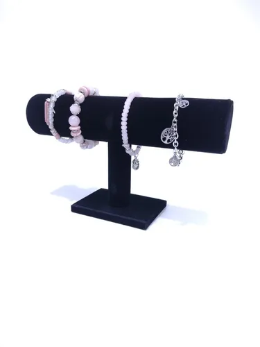 Expositor de joyas de terciopelo negro que contiene tres pulseras de cuentas.