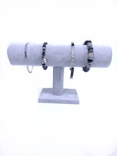 Expositor de joyas de color gris con cuatro pulseras sobre fondo blanco.