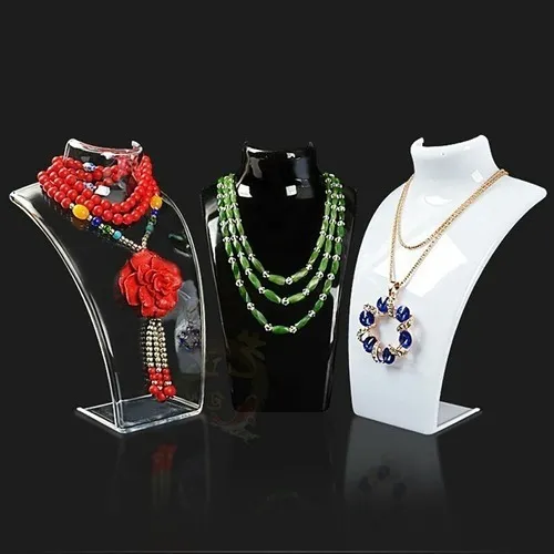 Tres exhibidores de collares con joyas: collares rojos, verdes y dorados sobre soportes blancos y negros.