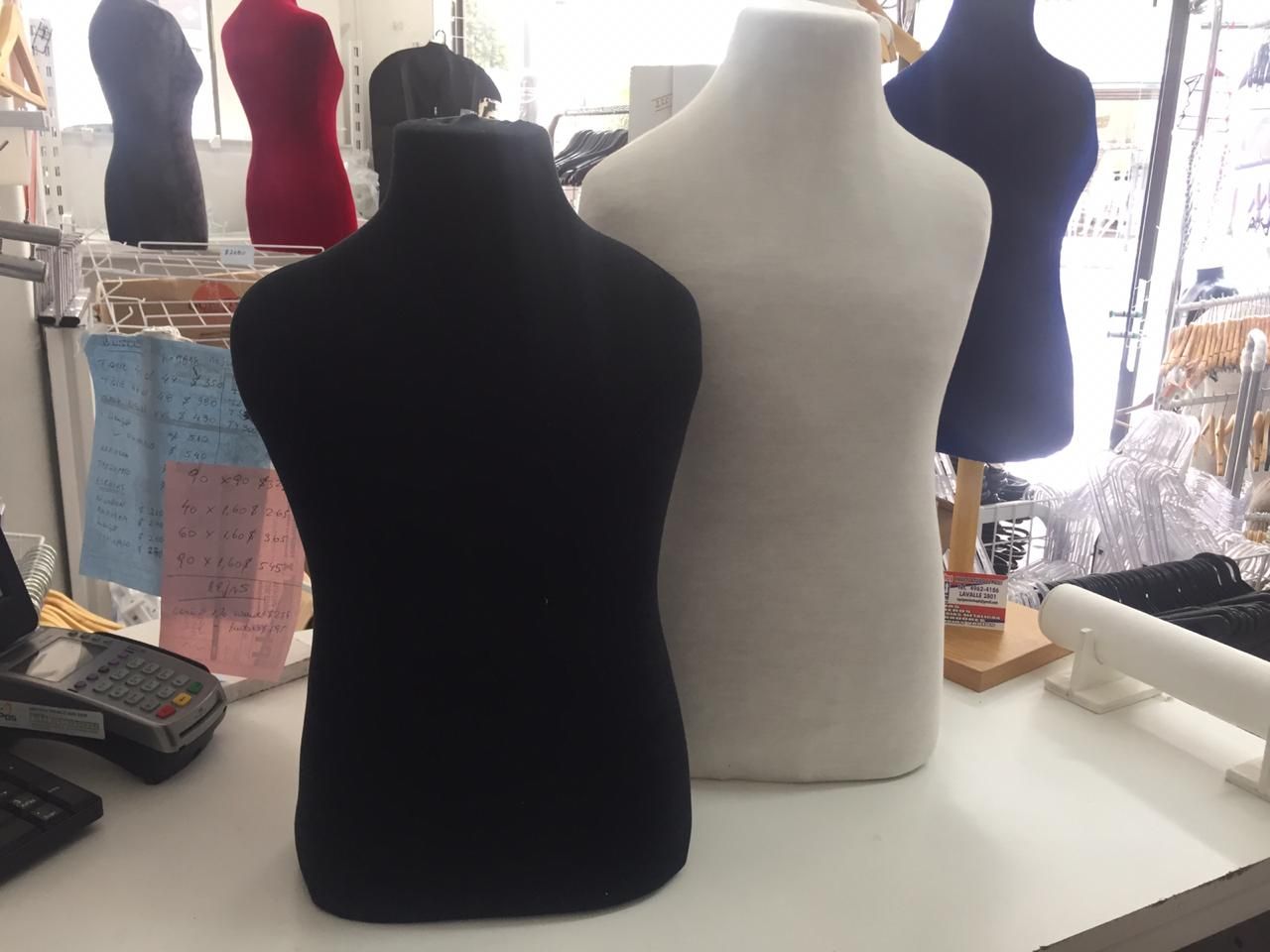 Maniquíes en blanco y negro sobre una mesa blanca, con otros maniquíes de colores en el fondo.